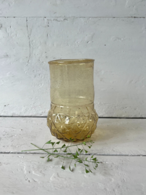 vaso piccolo ocra forma cilindrica con una parte superiore liscia e dritta, mentre la base è più ampia e decorata con un motivo a rilievo