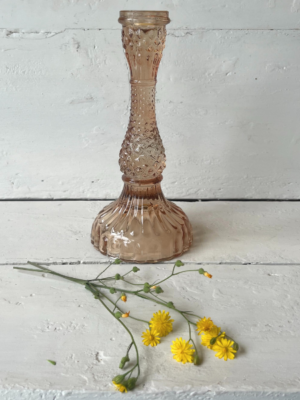 Candelabro in vetro trasparente rosa con una base ampia decorata con un motivo a rilievo. Il corpo del candelabro si restringe verso l'alto, terminando in un portacandele stretto e cilindrico.