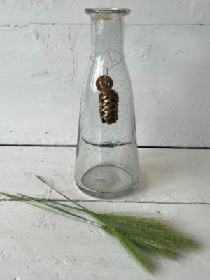 Vaso grande di forma conica, con una base ampia che si restringe gradualmente verso l'alto.  Attorno al collo del vaso è sospeso un piccolo ornamento metallico a forma di pigna