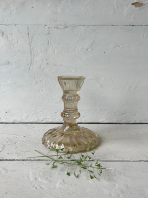 Candelabro in vetro trasparente ocra con una base ampia decorata con un motivo a rilievo. Il corpo del candelabro si restringe verso l'alto, terminando in un portacandele stretto e cilindrico.